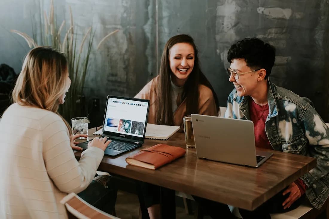 Three peoples that seems working are laughing around a table